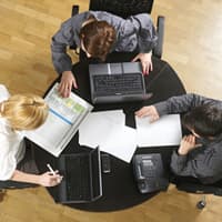 Three people working around a desk