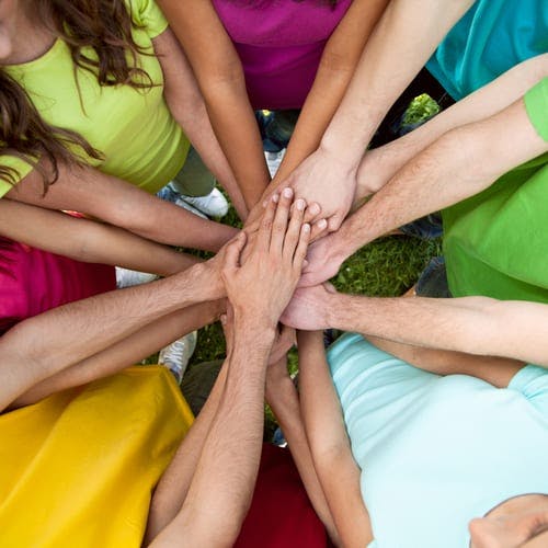 People in a circle with hands in the middle