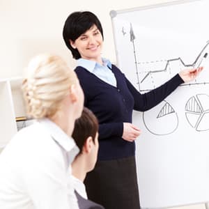 Woman making speech, in front of whiteboard