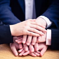 Employees putting their hands in a pile on table