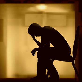 Silhouette of an upset man, sitting on a chair