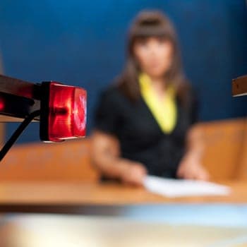 Newsreader sitting behind camera