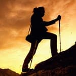 man climbing mountain at sunset